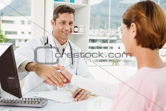 Doctor and patient shaking hands in medical office