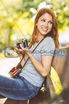 Redhead sitting on bench using her camera