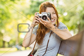 Redhead sitting on bench taking a photo