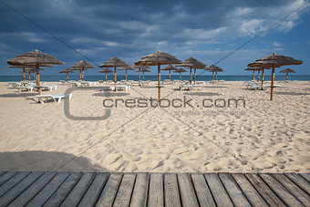 Different parasols and sun loungers on the empty beach on Tavira
