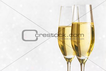 a pair of flutes of golden champagne on silver bokeh