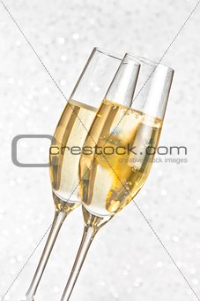a pair of flutes of golden champagne on silver bokeh