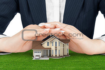 Female hands saving small house with a roof (concept)