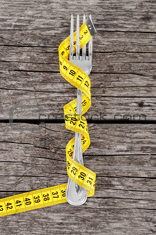 Fork and measuring tape on a thin wooden background