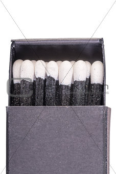 Black matches in a box on a white background macro
