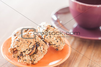 Closeup cereal cookies on orange plate and coffee cup