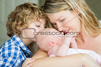 Young Mother Holds Newborn Baby Girl as Brother Looks On