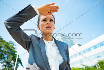 Serious business woman in front of office building looking into 