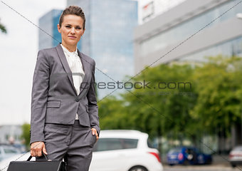 Portrait of business woman with briefcase standing in office dis