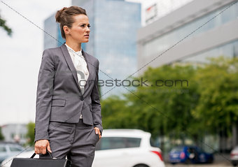 Business woman with briefcase standing in office district and lo