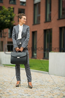 Full length portrait of business woman with briefcase in front o
