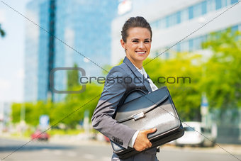 Portrait of smiling business woman with briefcase in office dist