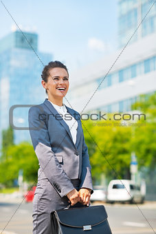 Happy business woman with briefcase in office district