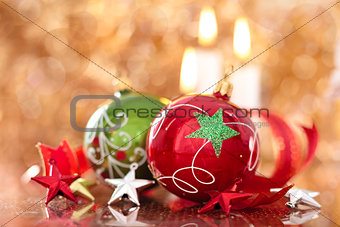 Christmas balls with stars and candles against holiday lights.