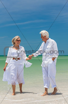 Happy Senior Couple Walking Holding Hands On Beach
