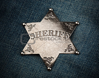 Sheriff star badge on blue denim background
