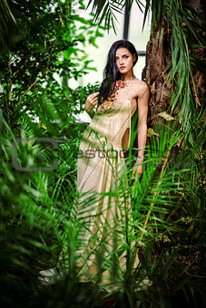 Gorgeous young woman in long evening dress in a forest