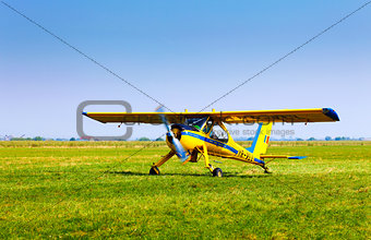 Retro yellow airplane on a green grass field preparing to take o