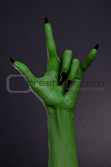 Green hand with black nails showing heavy metal gesture 