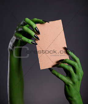 Green monster hands holding empty piece of cardboard 