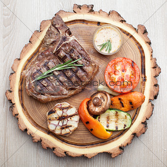 Portion of BBQ t-bone steak with  sauce  and grilled vegetables