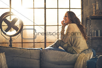 Young woman talking cell phone in loft apartment
