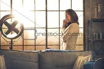 Young woman talking mobile phone in loft apartment