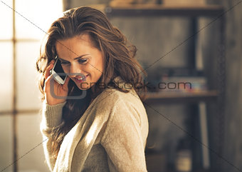 Portrait of young woman talking cell phone in loft apartment