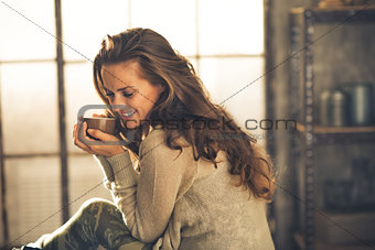 Portrait of relaxed young woman with cup of coffee in loft apart