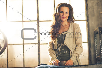 Portrait of happy young woman with cup of coffee in loft apartme