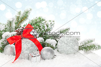 Christmas baubles and red ribbon over snow bokeh background