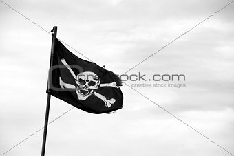 Torn Jolly Roger flies from flagpole