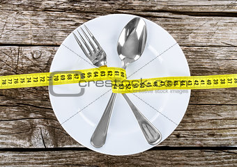 Fork and measuring tape on a thin wooden background