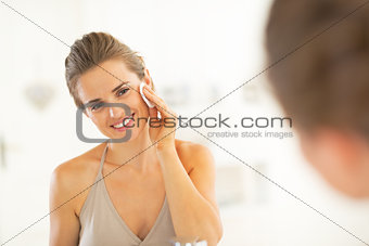 Portrait of happy young woman using cotton pad in bathroom