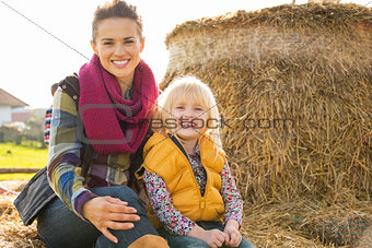 Portrait of happy mother and child sitting on haystack