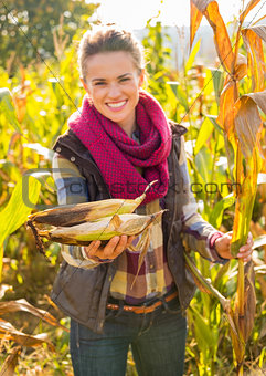 Closeup on smiling young woman giving corns while in cornfield