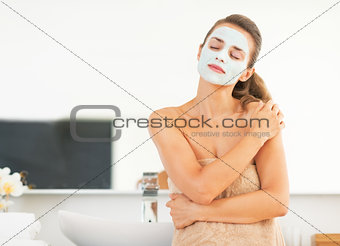 Portrait of young woman with facial cosmetic mask in bathroom