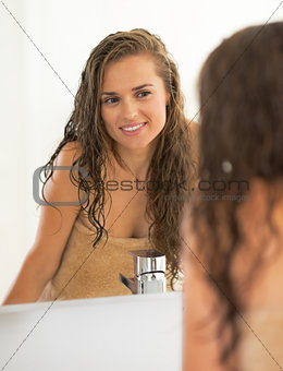 Portrait of happy young woman with wet hair in bathroom looking 