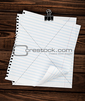 two sheets of notebook held together on a wooden background