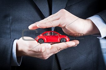 businessman protect with his hands a red car, concept for insurance, buying, renting, fuel or service and repair costs 