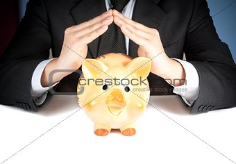 a businessman make with his hand a home behind a piggy bank, concept for business and save money