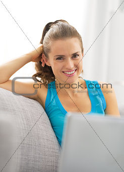 Portrait of happy young woman with laptop in living room