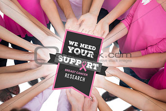 Composite image of hands joined in circle holding breast cancer struggle symbol