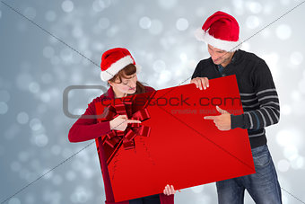 Couple holding a sign with red ribbon