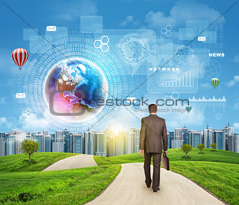 Businessman walks on road. Rear view. Buildings, grass field and sky with virtual elements