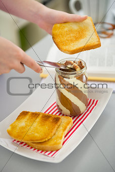 Closeup on young woman spread toast with chocolate cream