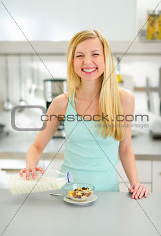 Young woman pouring milk into muesli