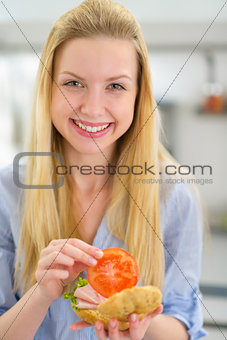 Smiling young woman making sandwich