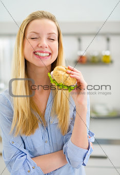Smiling young woman eating sandwich