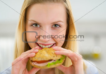 Portrait of happy young woman eating sandwich